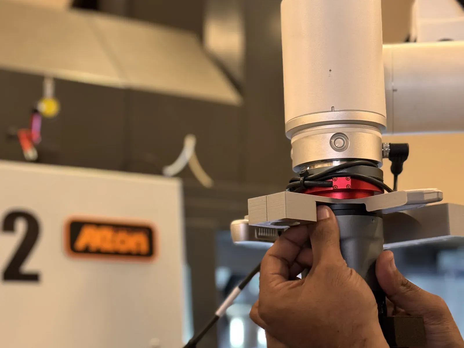 Hands adjusting a robotic gripper on a cobot arm during testing