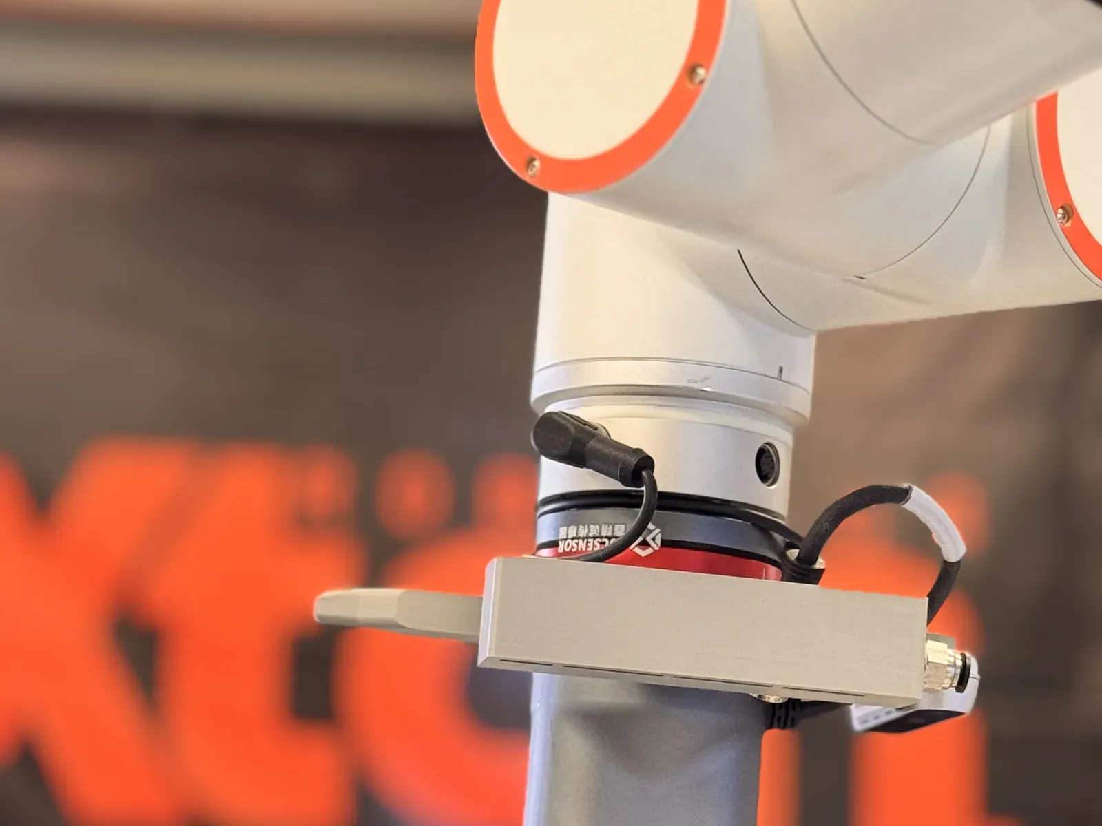 Close-up of a cobot arm and robotic gripper in front of the Axton Robotics banner