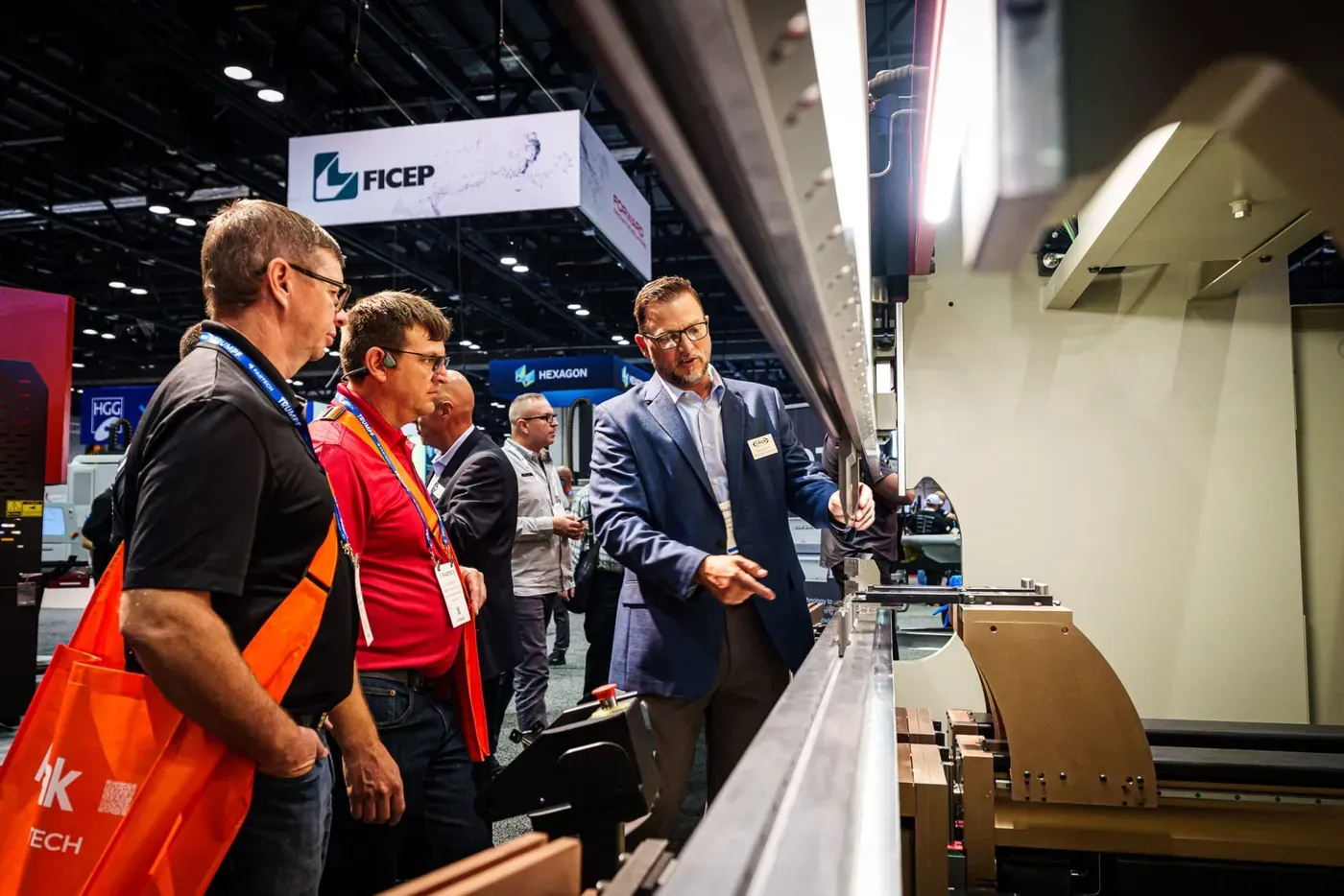 Visitors examining a machine at an exhibitor booth at FABTECH