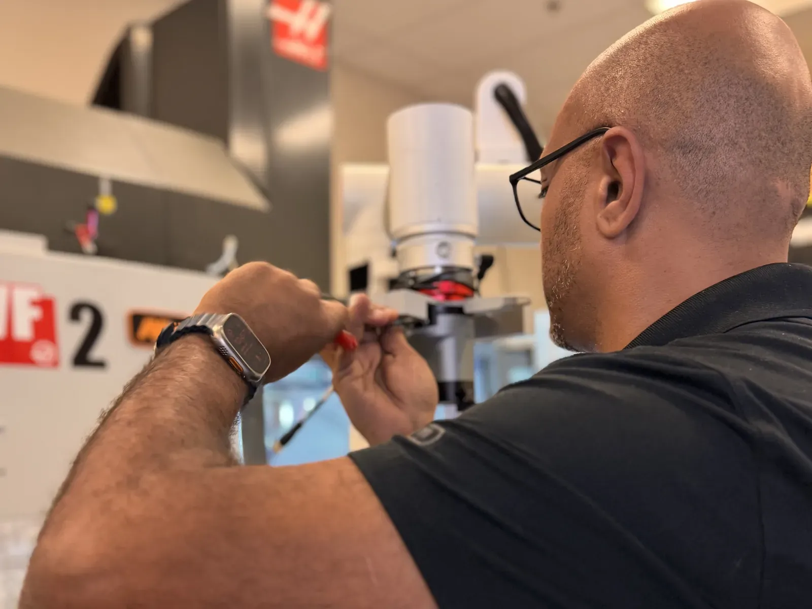 Michael Nessim fitting a robotic gripper to a cobot arm next to a Haas CNC mill