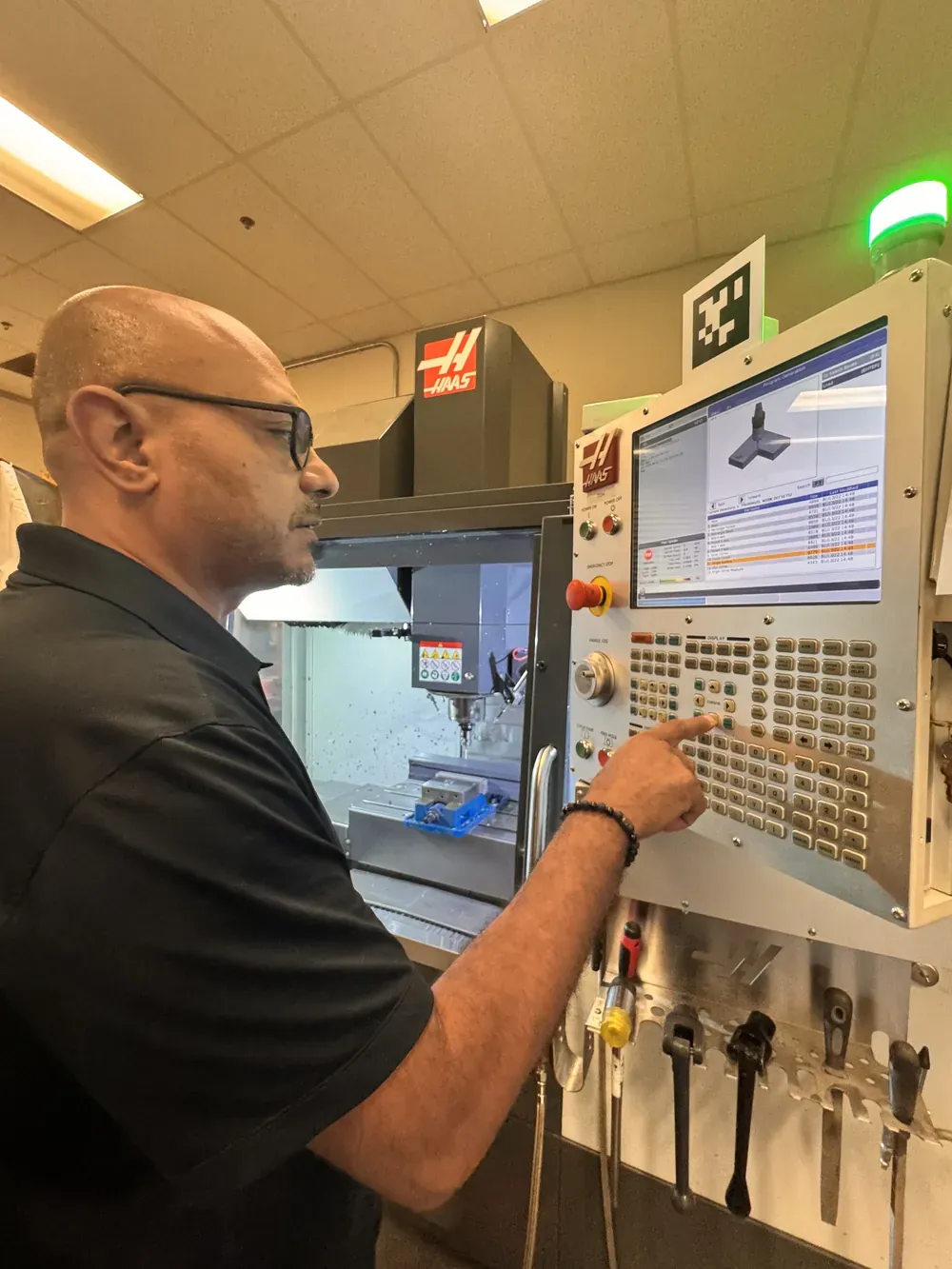 Michael Nessim at a Haas CNC control panel with an AprilTag marker mounted on top of the screen