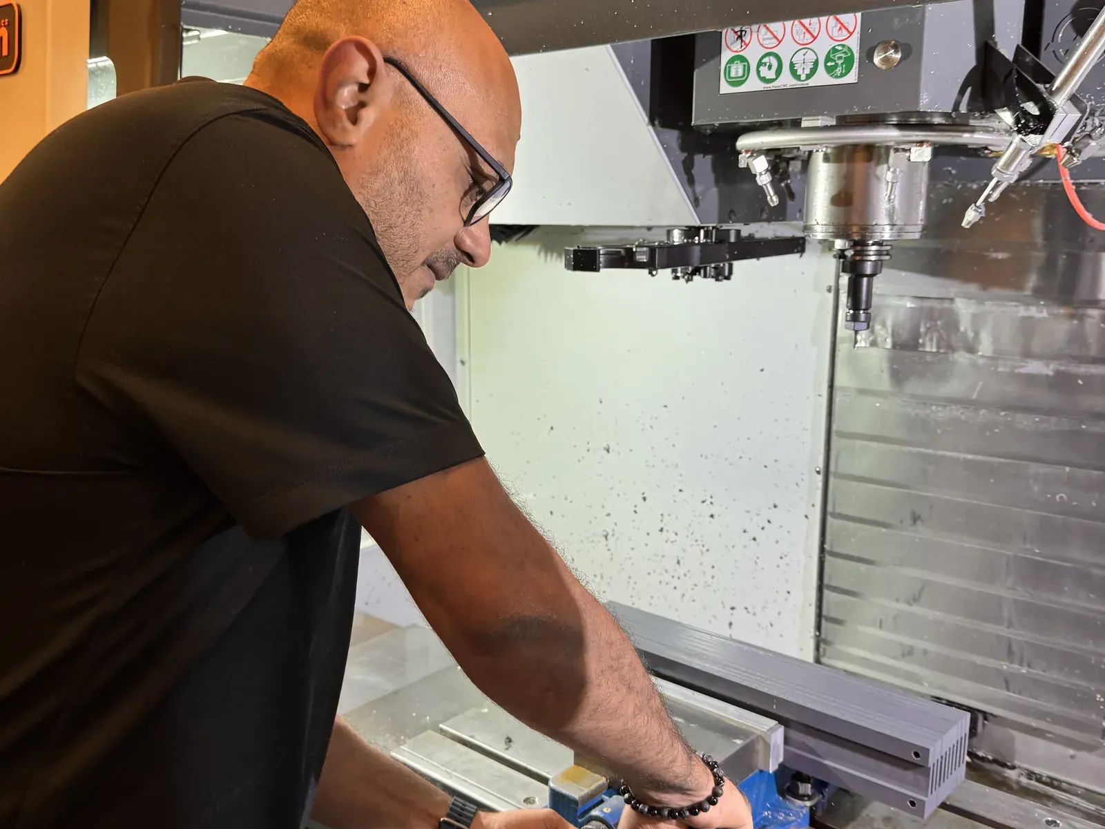 Michael Nessim of Axton Robotics loading a part into the vise of a Haas VF-2 CNC mill by hand