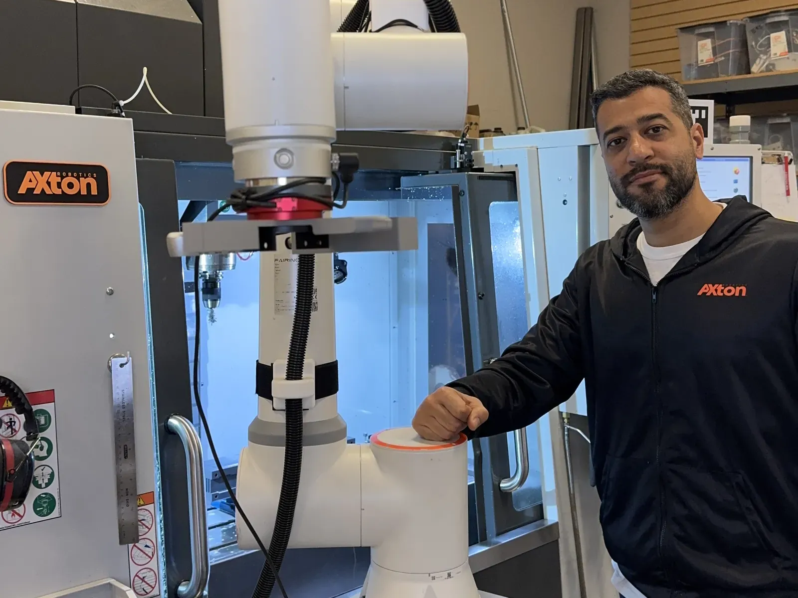 Malak Mitch of Axton Robotics beside a cobot rolled up to a Haas CNC mill