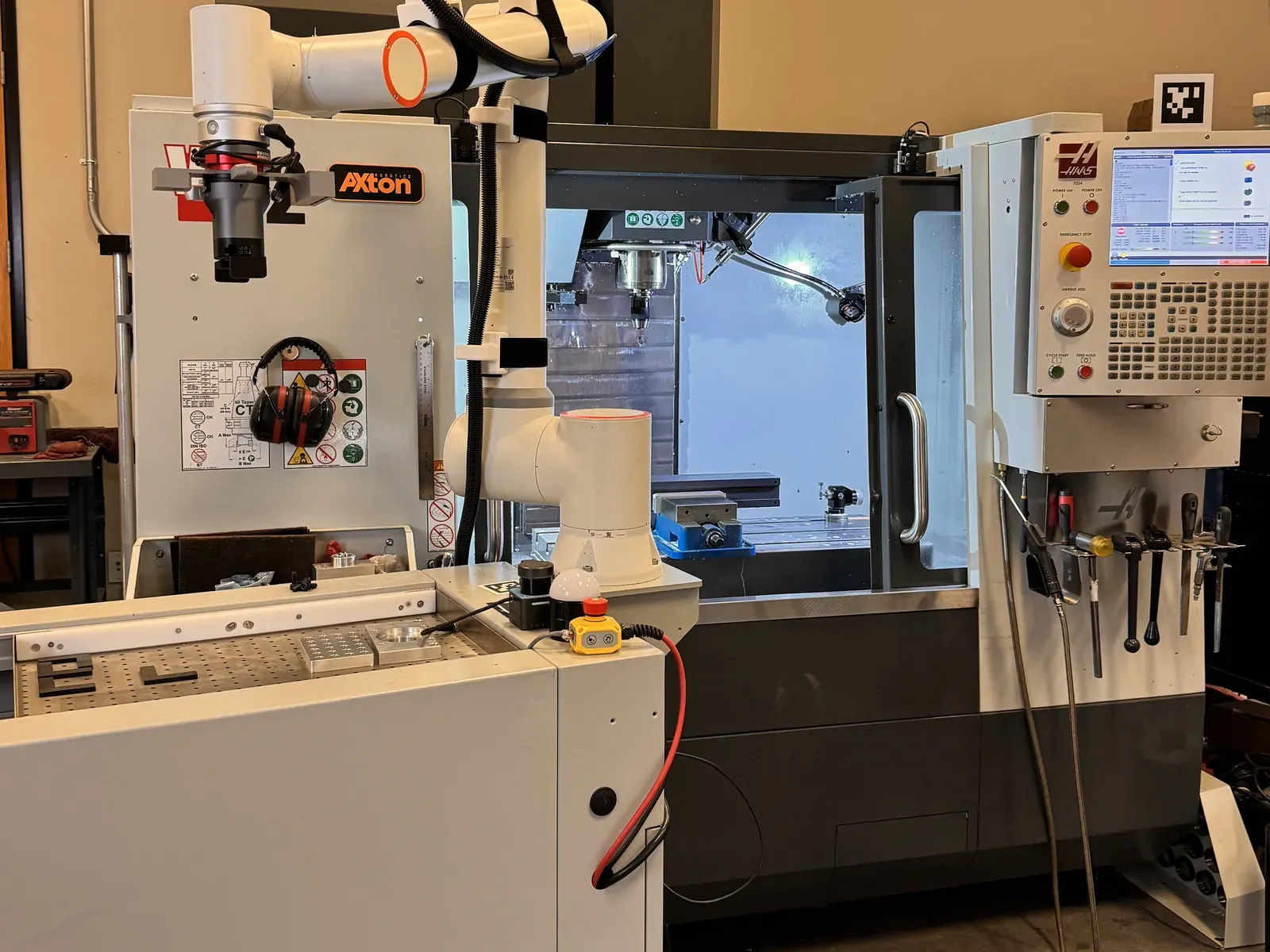 Mobile cobot machine tending station rolled up to a Haas VF-2 CNC mill in the Axton Robotics test cell