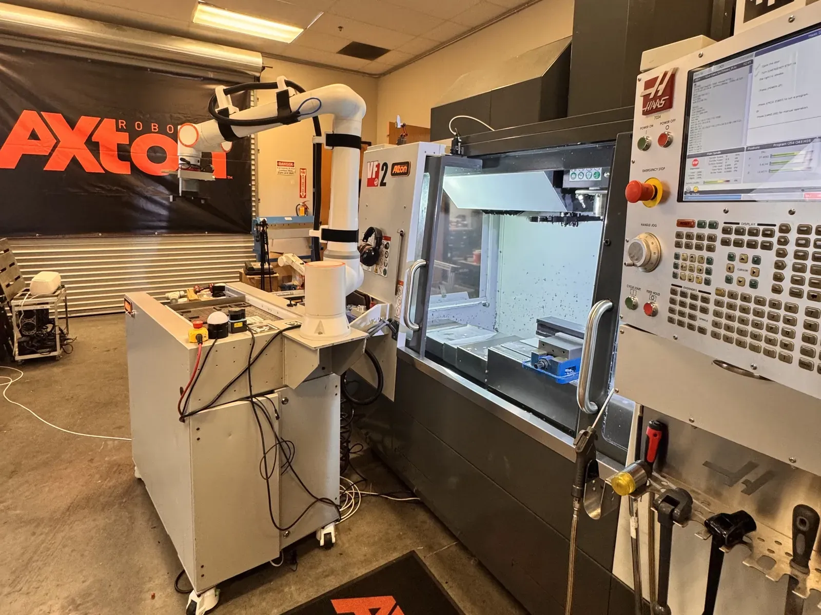 Mobile Axton Robotics machine tending station on wheels beside a Haas CNC mill