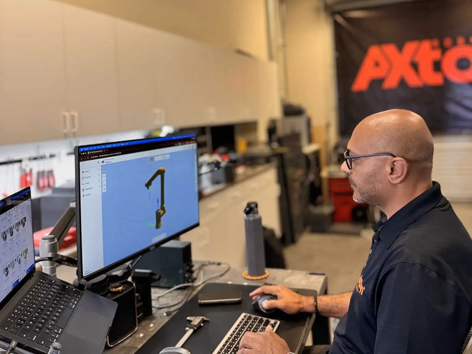 Michael Nessim testing robot arm motion software on a computer in the Axton Robotics lab