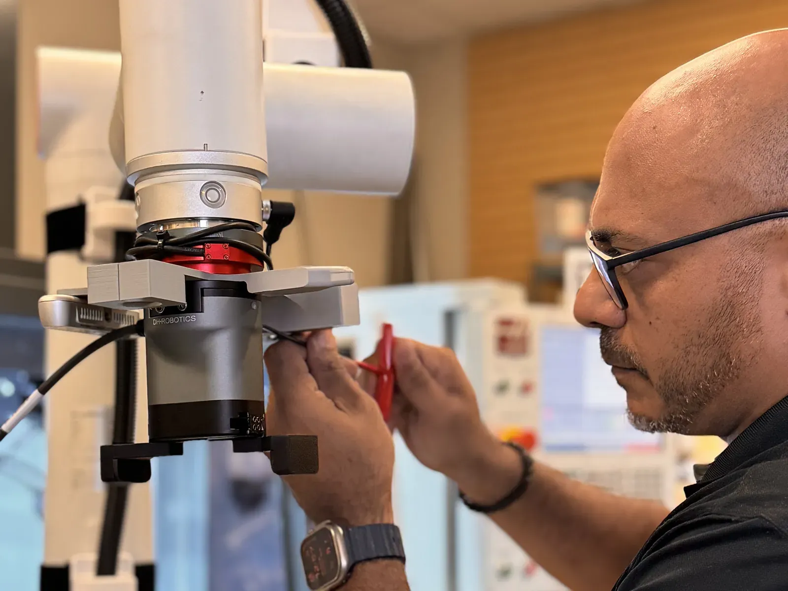 Axton Robotics engineer adjusting a robotic gripper on a cobot arm while prototyping a CNC machine tending cell