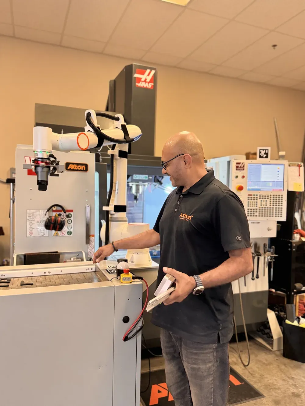 Michael Nessim using a mobile cobot station rolled up to a standard Haas CNC mill