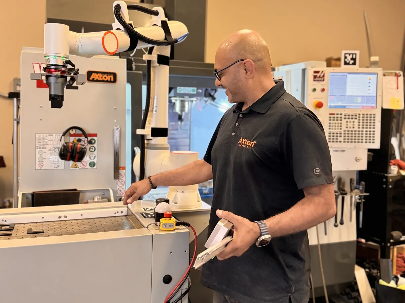 Michael Nessim using a mobile cobot station rolled up to a standard Haas CNC mill