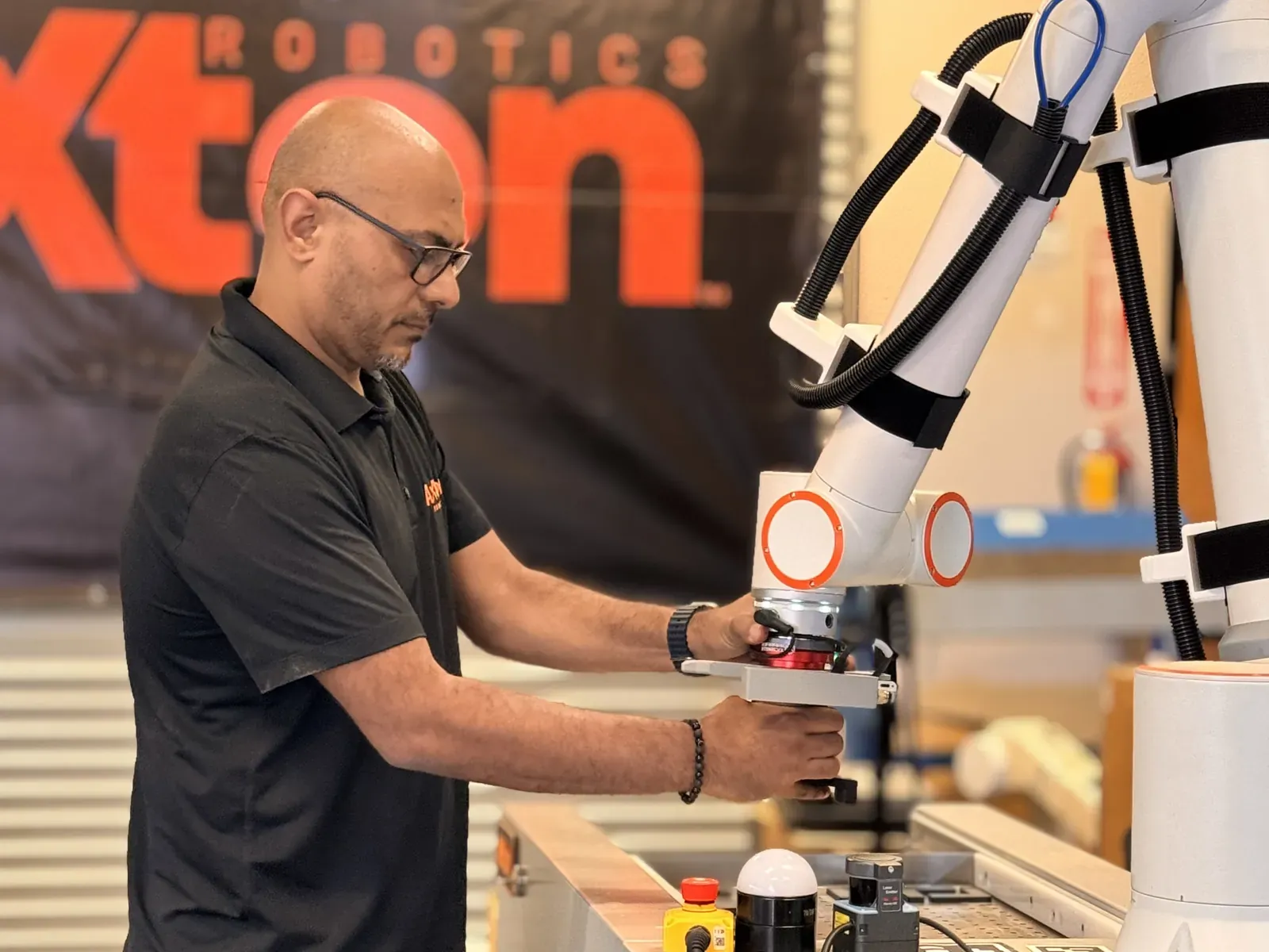 Michael Nessim teaching a cobot a job by hand in front of the Axton Robotics banner
